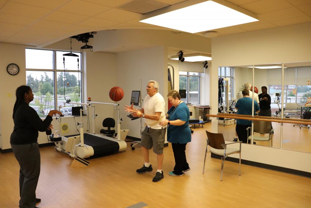 With the help of physical therapist Mary Beth O’Reilly, Corbin Cash plays catch with a physical therapy assistant while walking side-to-side.