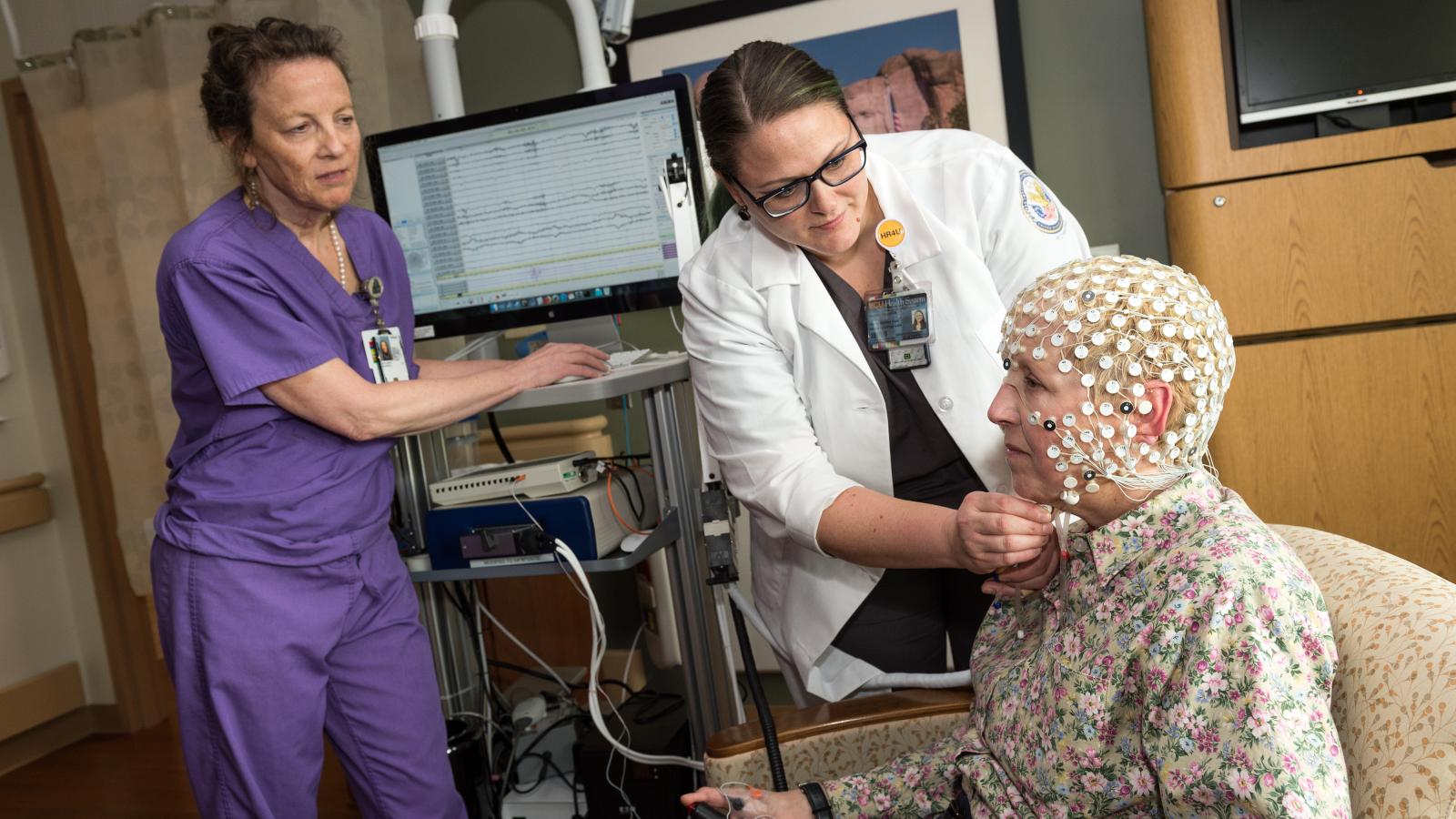 Kathryn Holloway, M.D. (left), observes Rachel Van Aken as she adjusts a 256-electrode cap that Dr. Holloway’s team is using in preclinical studies to identify signatures of various parts of the brain that will serve as guides when surgeons target cognitive challenges, such as dementia, using deep brain stimulation. Photo: Kevin Schindler