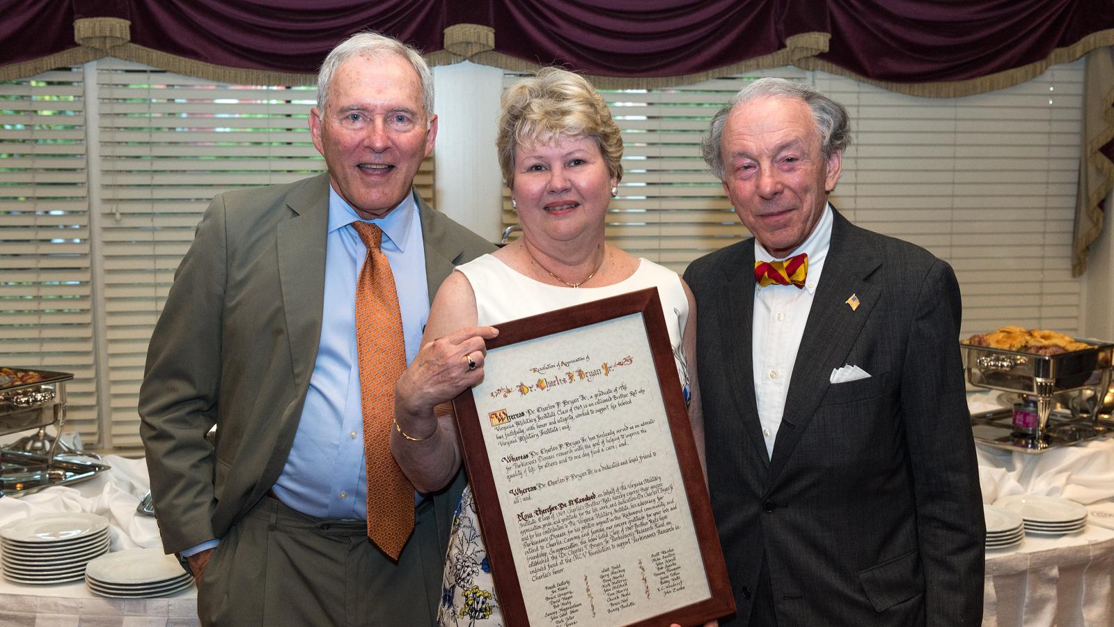 Charlie Bryan and his wife Cammy Bryan, along with John Ishon, look over a resolution in appreciation of Charlie that was presented at the reception where the Dr. Charles F. Bryan Jr. Parkinson’s Research Fund was announced.